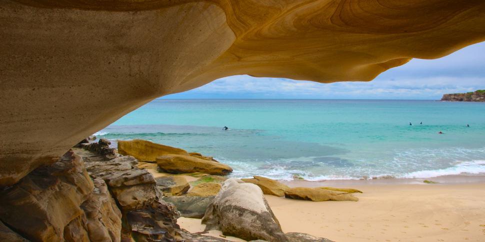 Free Image of A breathtaking beach view through a rocky archway 