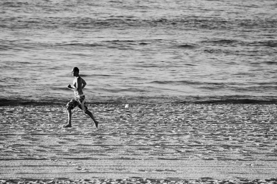 Free Image of A boy running joyfully along the beach by the sea. 