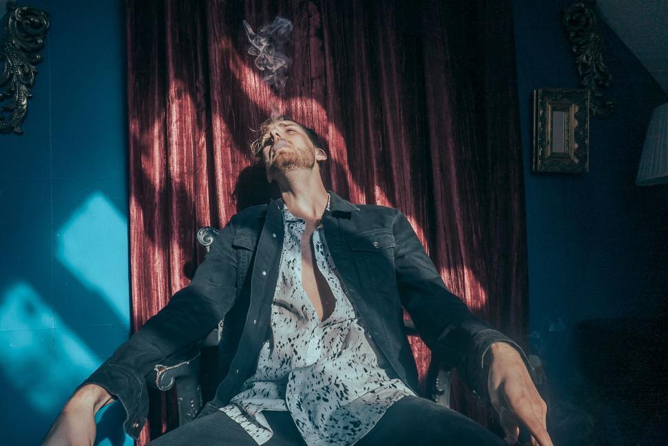 Free Image of Man relaxing in a chair with smoke rising, artistic vibe 
