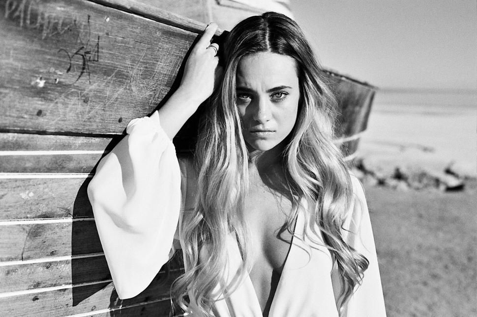 Free Image of Woman with long hair posing near rustic wooden boat. 
