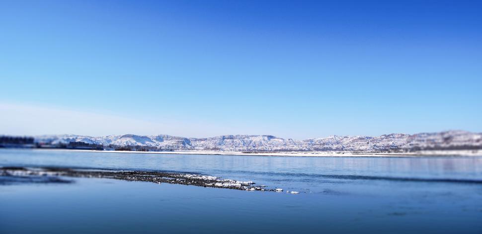 Free Image of Expansive view of a calm lake with distant mountains 