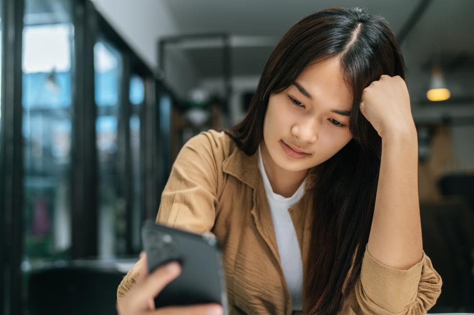 Free Image of Young woman bored during video call on smartphone at cafe 