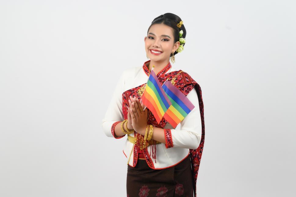 Free Image of Portrait of Young woman in Thai Northeastern Traditional Clothing holding rainbow flag 