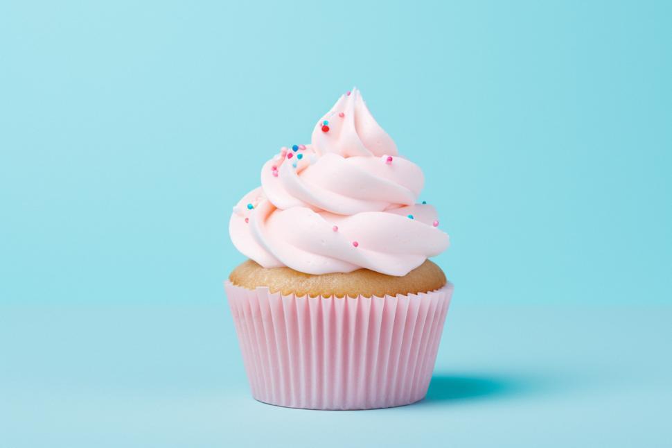 Free Image of Delicious pink frosted cupcake on a blue background 
