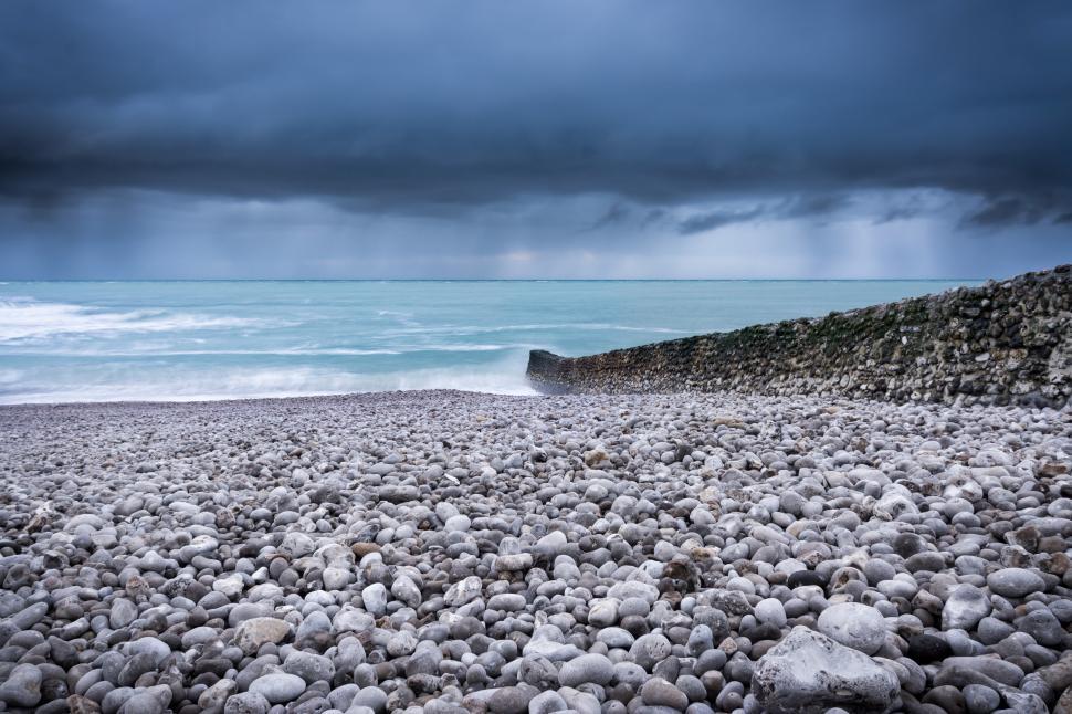 Free Image of Dark clouds gather over rocky beach at twilight 