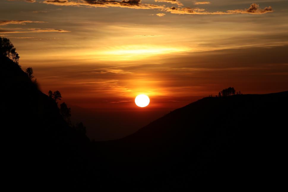 Free Image of Stunning sunset over hills in serene evening glow 
