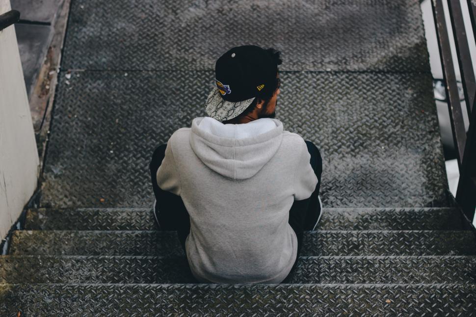 Free Image of Man sitting on metal stairs in an urban environment during an overcast day 