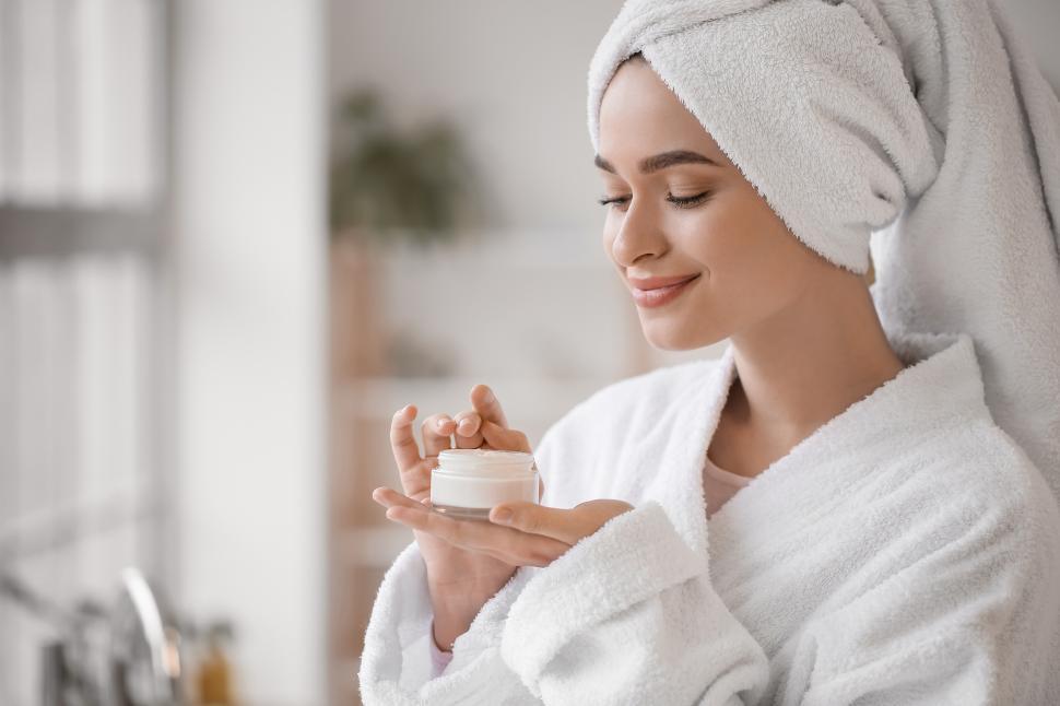 Free Image of Woman applying skincare product in bathroom setting 