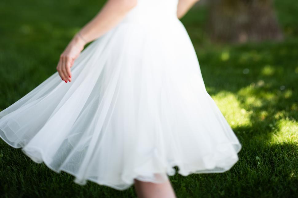 Free Image of Bride twirls in a flowing white dress on a sunny day 