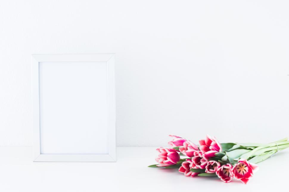 Free Image of Floral arrangement beside a blank picture frame 