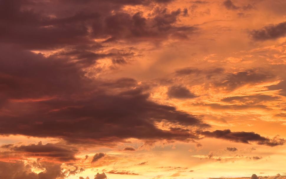 Free Image of Stunning sunset clouds over a serene landscape at dusk 