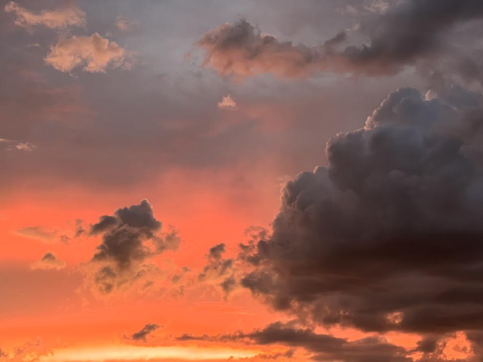 Free Image of Vibrant sunset with dramatic clouds over a serene landscape 