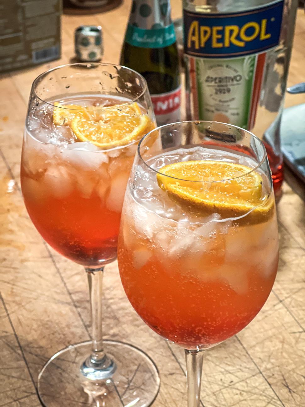 Free Image of Refreshing Spritz cocktails with orange slices on a wooden table during a gathering 
