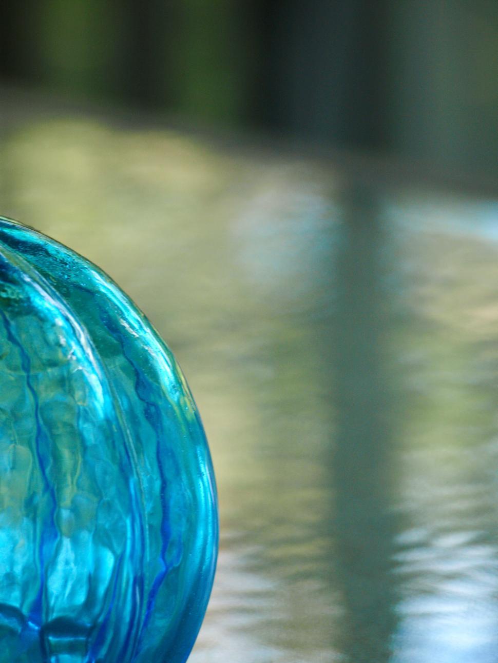 Free Image of Beautiful blue glass orb reflecting light near calm water surface 