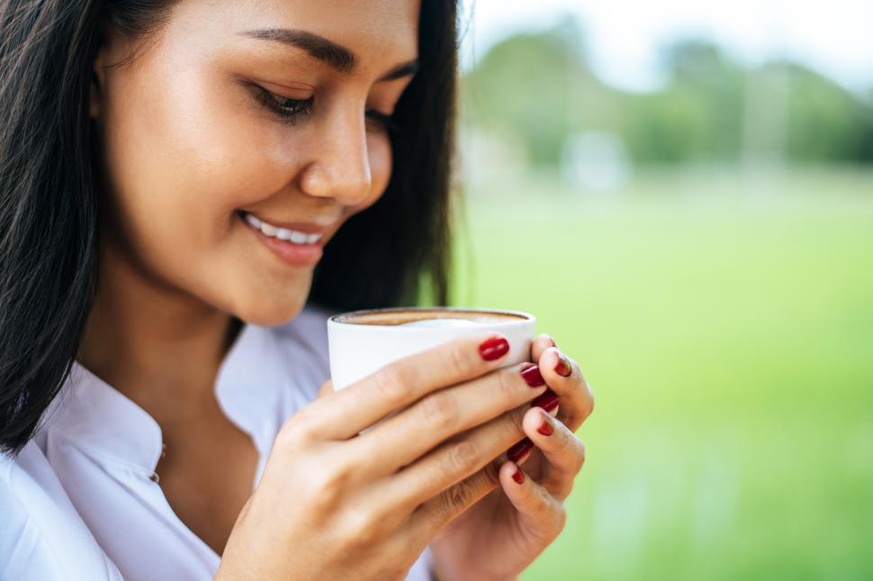 Free Image of That woman stood happily drinking coffee on the meadow. 