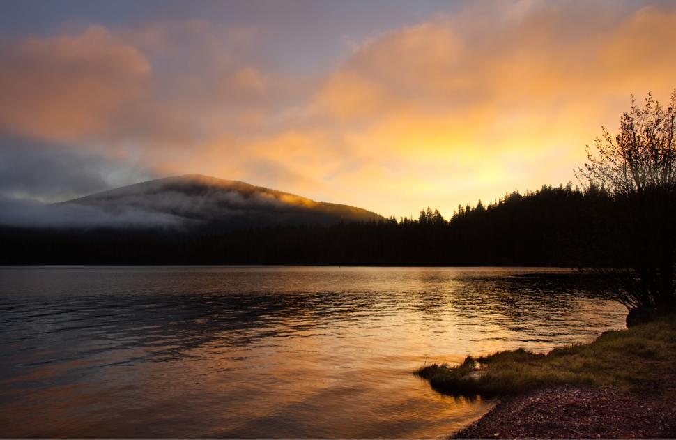 Free Image of Stunning sunset over tranquil lake with mountains in the background 