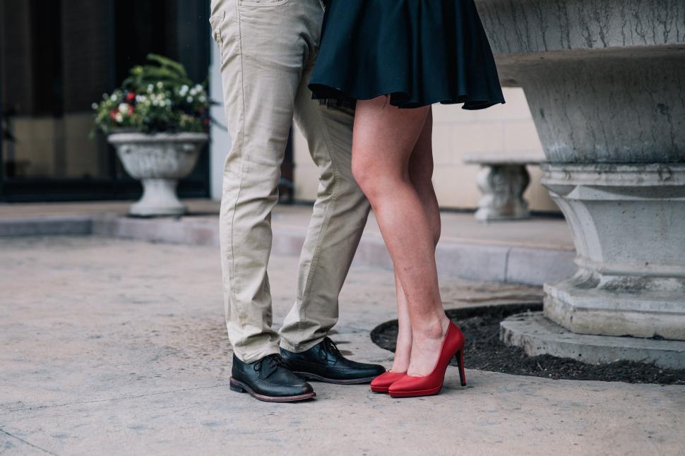Free Image of Couple standing by a fountain wearing stylish attire 