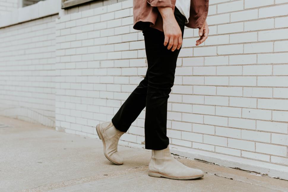Free Image of Man walking on sidewalk near brick wall during daytime 