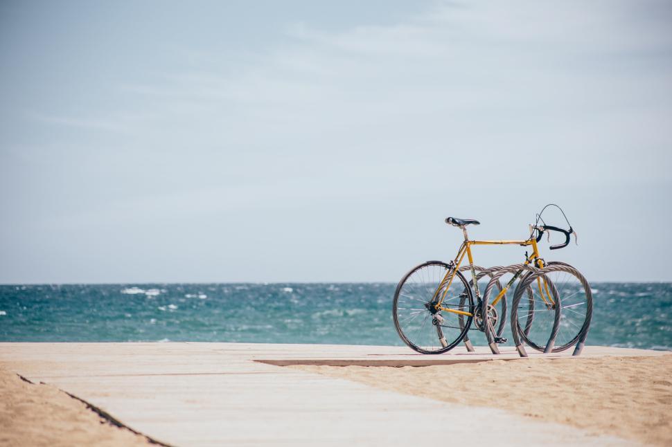 Free Image of Bicycle parked on sandy boardwalk by the ocean shore 