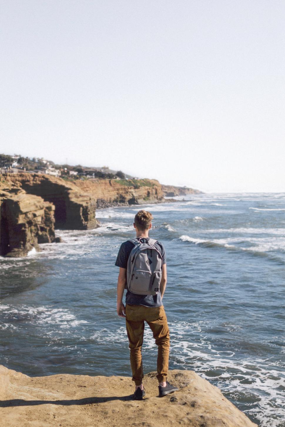 Free Image of Hiker gazes at ocean waves from scenic cliffs in a coastal landscape 