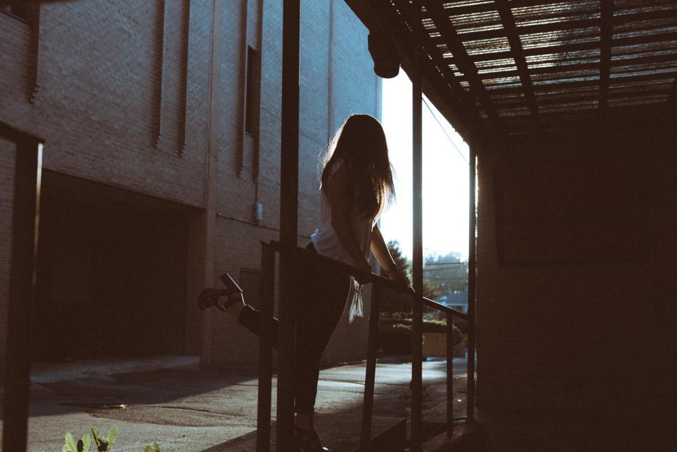 Free Image of Young woman leaning on railing during sunset 