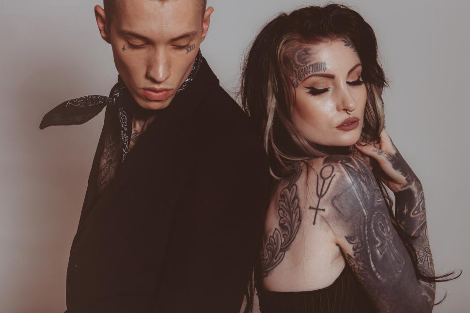 Free Image of Fashionable couple showcasing intricate tattoos in studio setting 