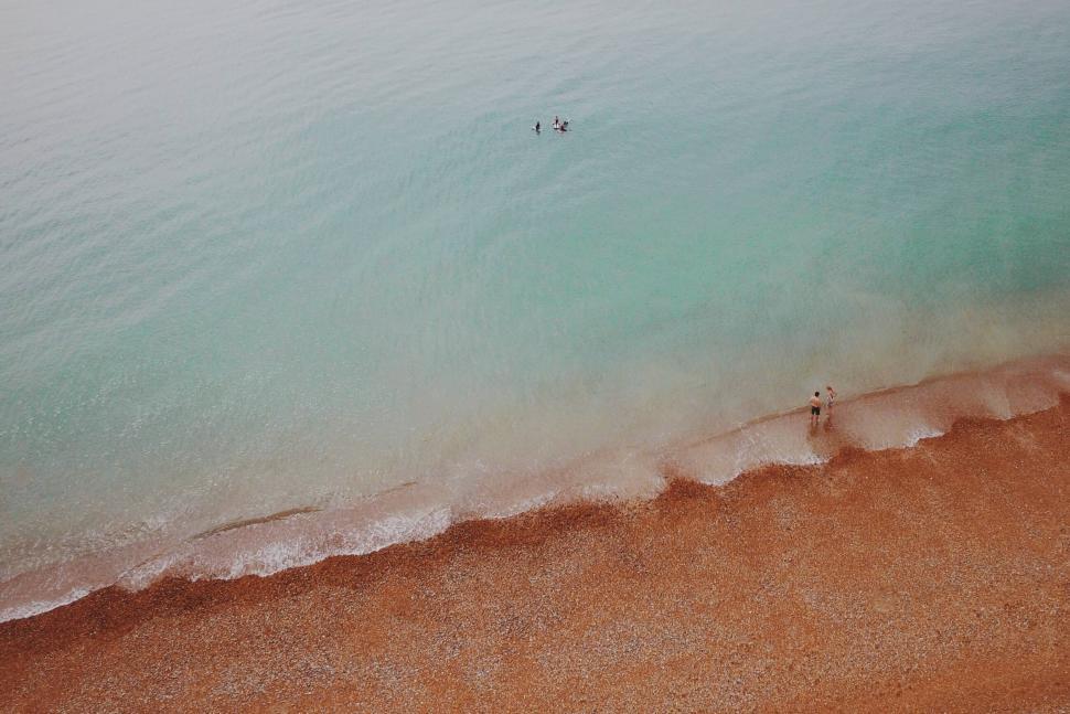 Free Image of People enjoying a quiet beach day at dawn with gentle waves 