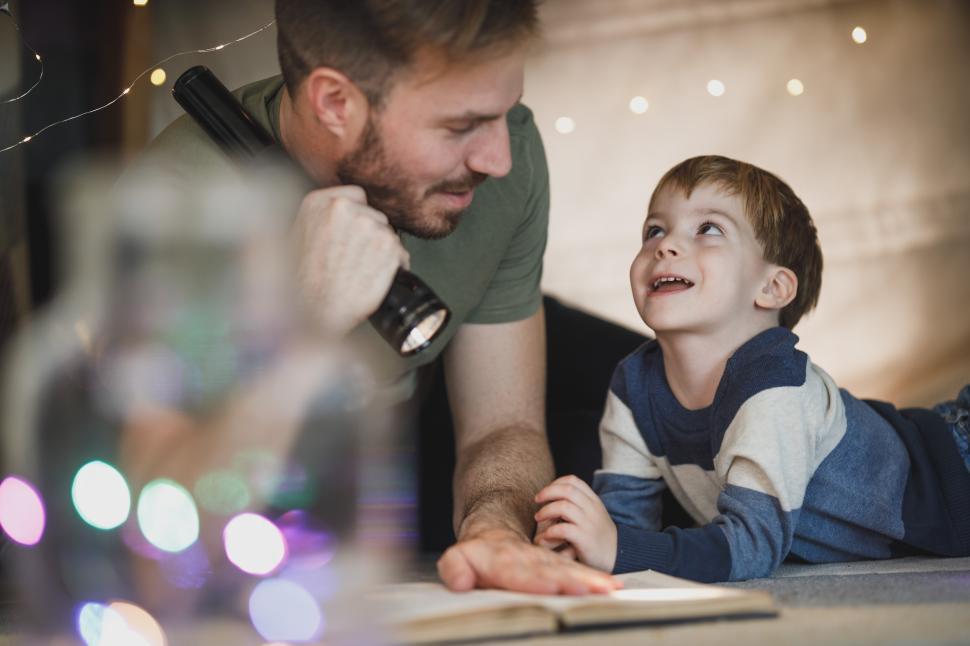 Free Image of Father and son enjoy storytelling with a flashlight indoors 