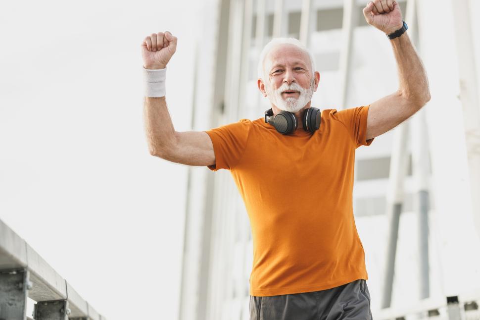 Free Image of Older man celebrating fitness achievement on urban bridge 