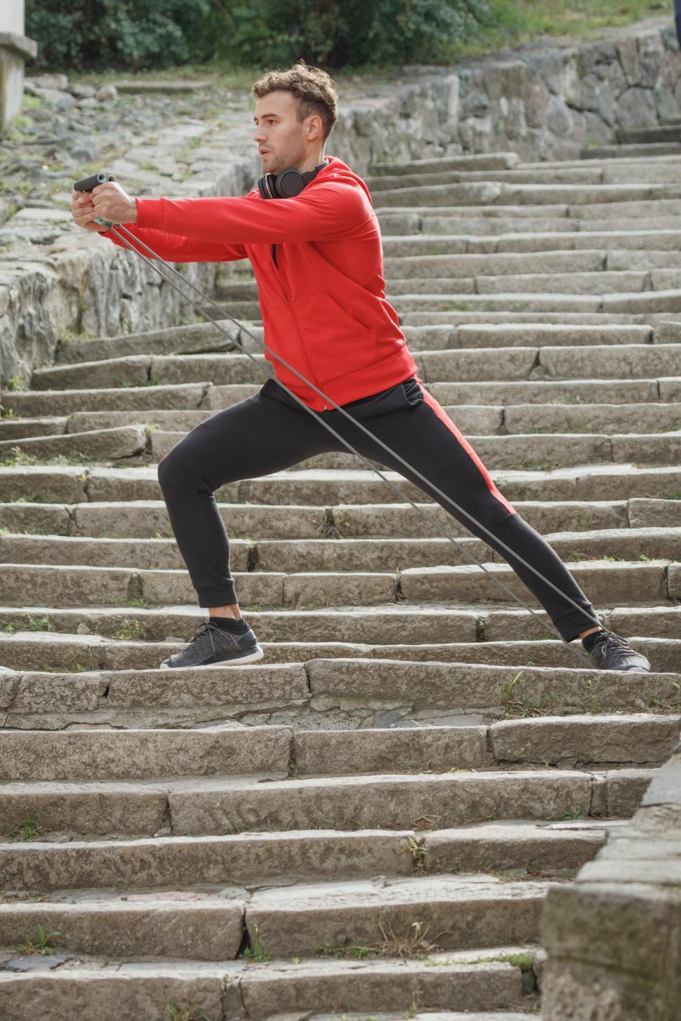 Free Image of Fitness enthusiast performs resistance band exercise on outdoor stairs 