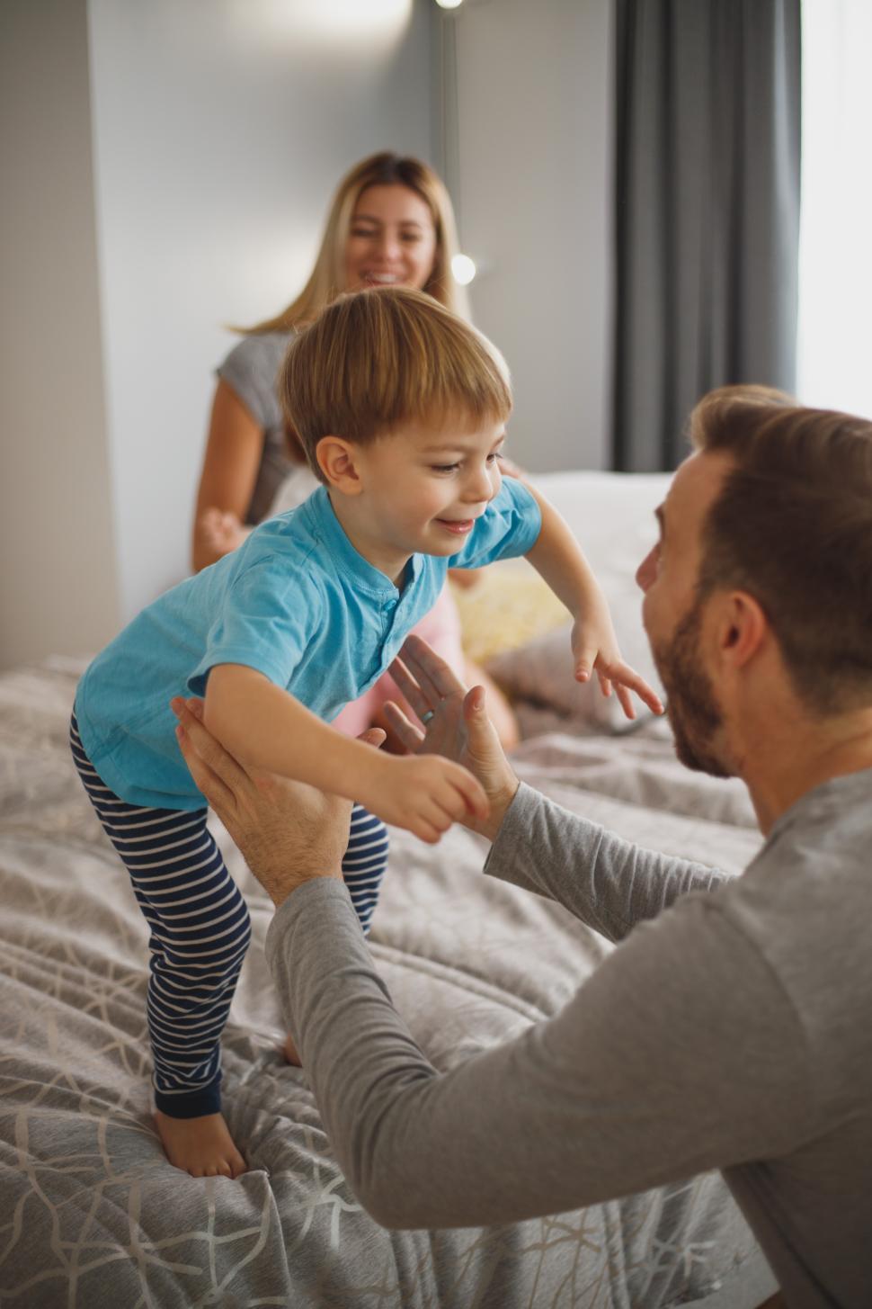 Free Image of Family joy as child jumps into dad s arms while mom smiles 