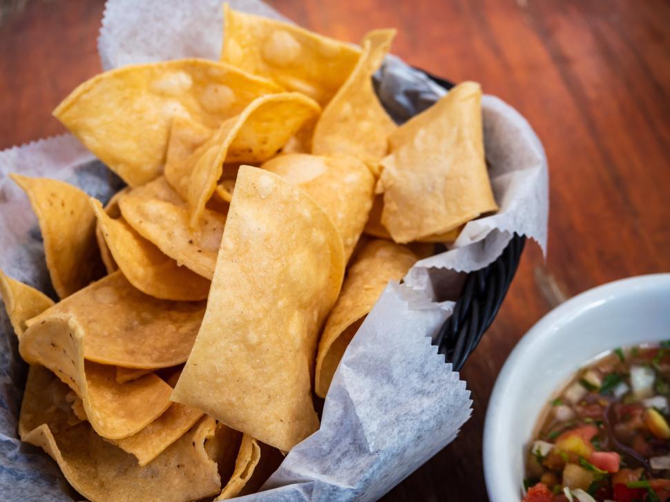 Free Image of Crispy tortilla chips served with fresh salsa in a cozy setting 