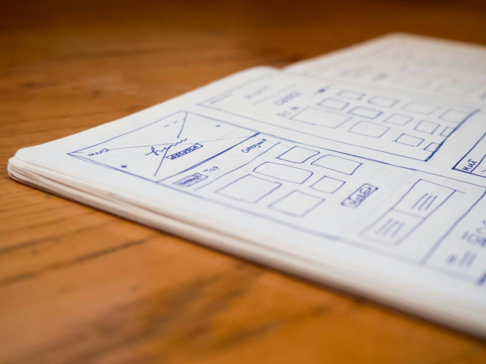 Free Image of Schematic designs and wireframes on paper laying on a wooden surface 