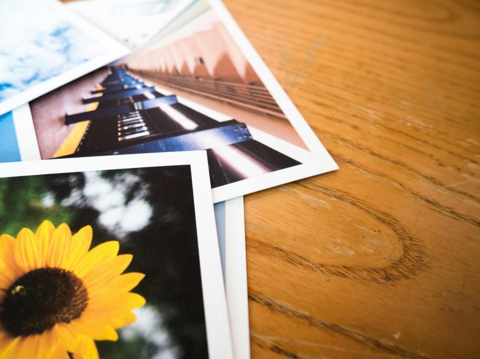 Free Image of Colorful collection of photographs on a wooden table showing various subjects 