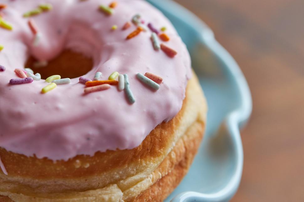 Free Image of Delicious pink frosted donut with sprinkles on a plate 
