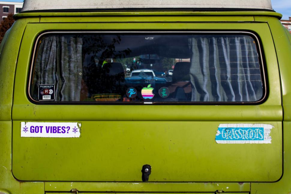 Free Image of Quirky green van with playful stickers parked in a vibrant urban setting 