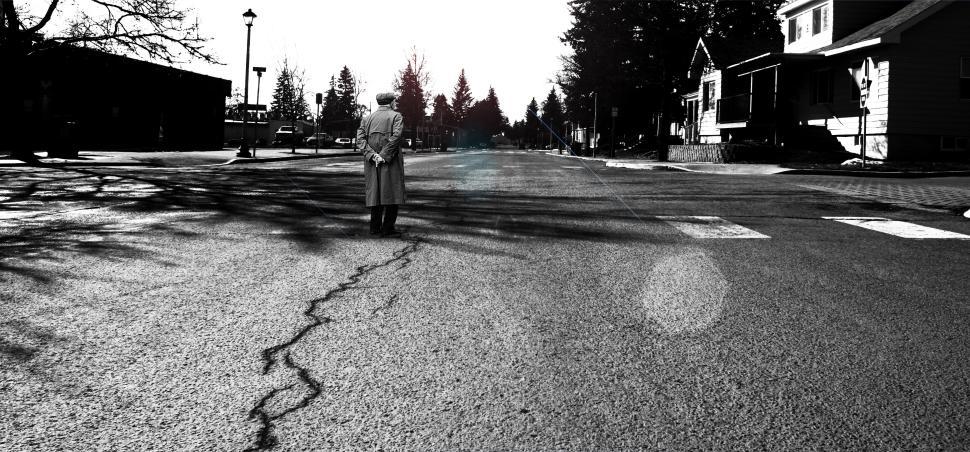Free Image of Elderly man standing alone on a quiet street during early morning light 