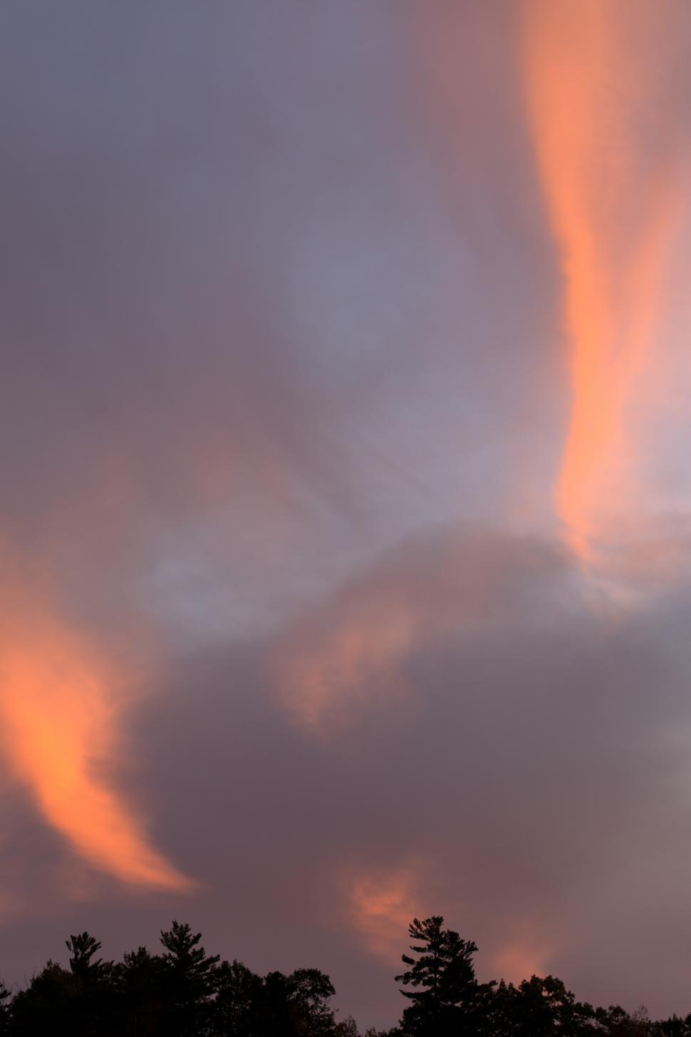 Free Image of Vibrant sunset clouds illuminate the evening sky over a tranquil landscape 