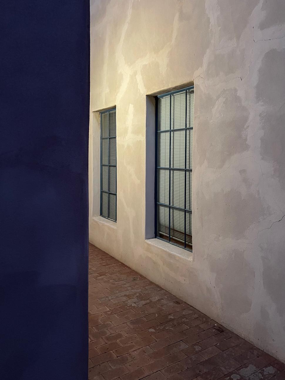 Free Image of Looking down a quiet alley with simple adobe walls 