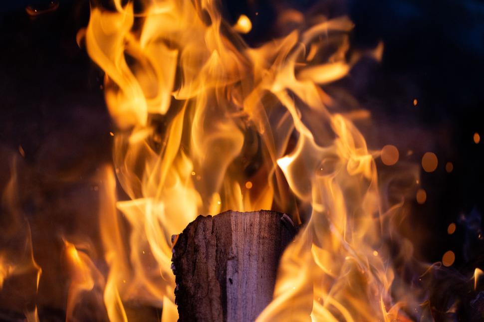 Free Image of Fire dances around a wooden log in the dark night sky during a cool evening gathering 