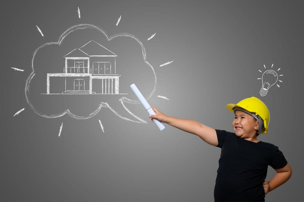 Free Image of A boy wearing a yellow engineer hat and a house plan on a blackboard 