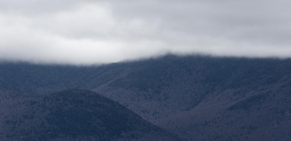 Free Image of Misty mountains shrouded in clouds on an overcast day in the wilderness 
