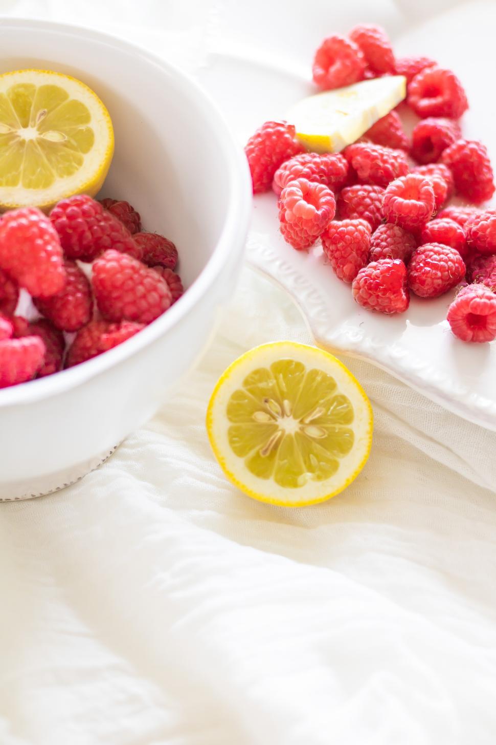 Free Image of Fresh raspberries and lemon on a light fabric background 