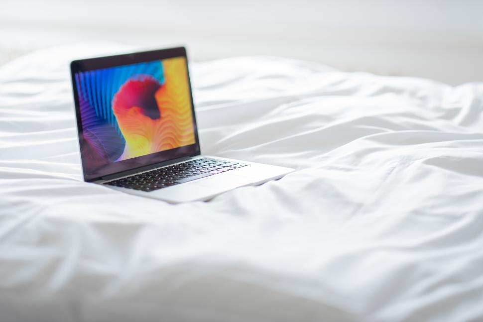 Free Image of Laptop on a bed with colorful screen display 