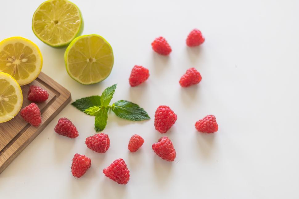 Free Image of Fresh raspberries and citrus fruits on a white surface 