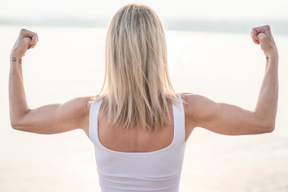 Free Image of Celebrating strength by a serene water body at sunset 