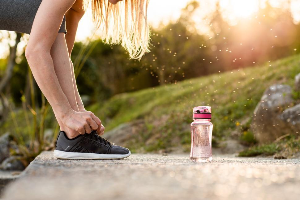 Free Image of Runner ties shoelaces before workout at sunset 