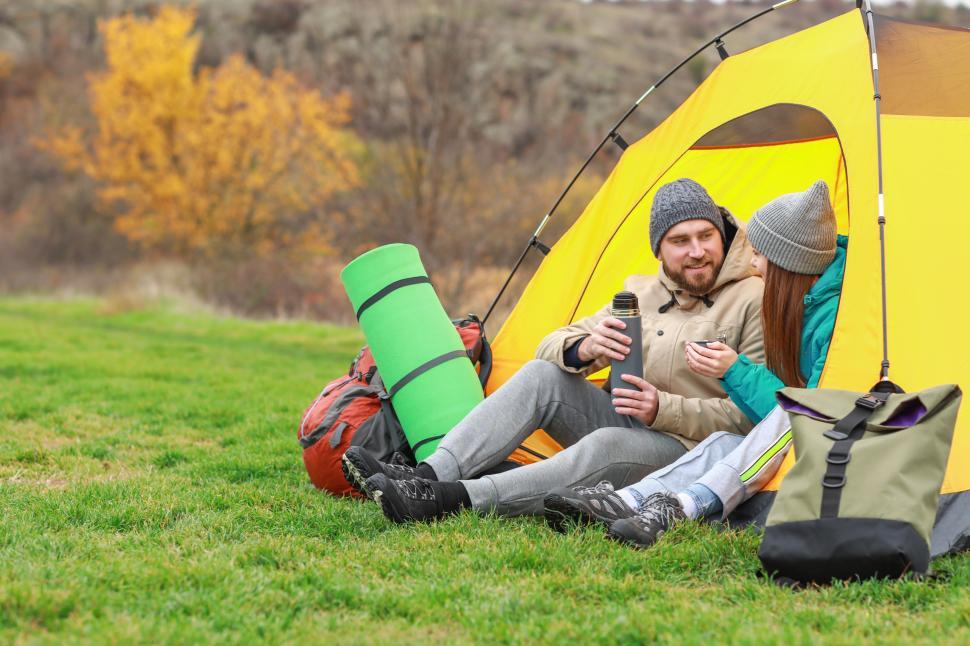 Free Image of Couple enjoying a relaxing moment outside their tent in autumn 