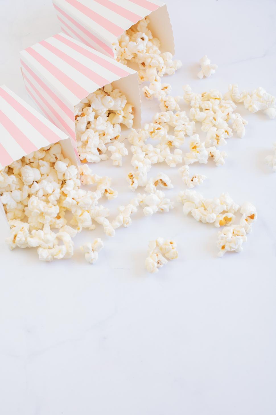 Free Image of Freshly popped popcorn spilling from striped containers 