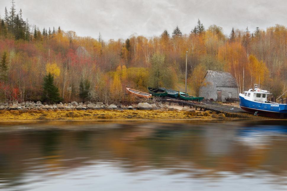 Free Image of Boats docked by a serene river in autumn colors 